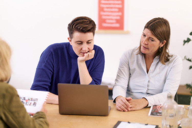 Zwei Personen am Schreibtisch besprechen etwas am Laptop