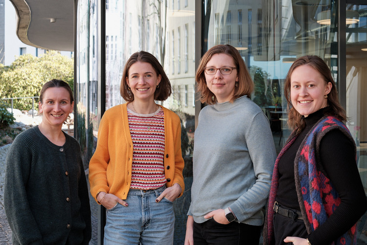 Unsere vier Kolleginnen, die im Themenfeld Wirkung und Evaluation arbeiten stehen vor einer Glaswand.