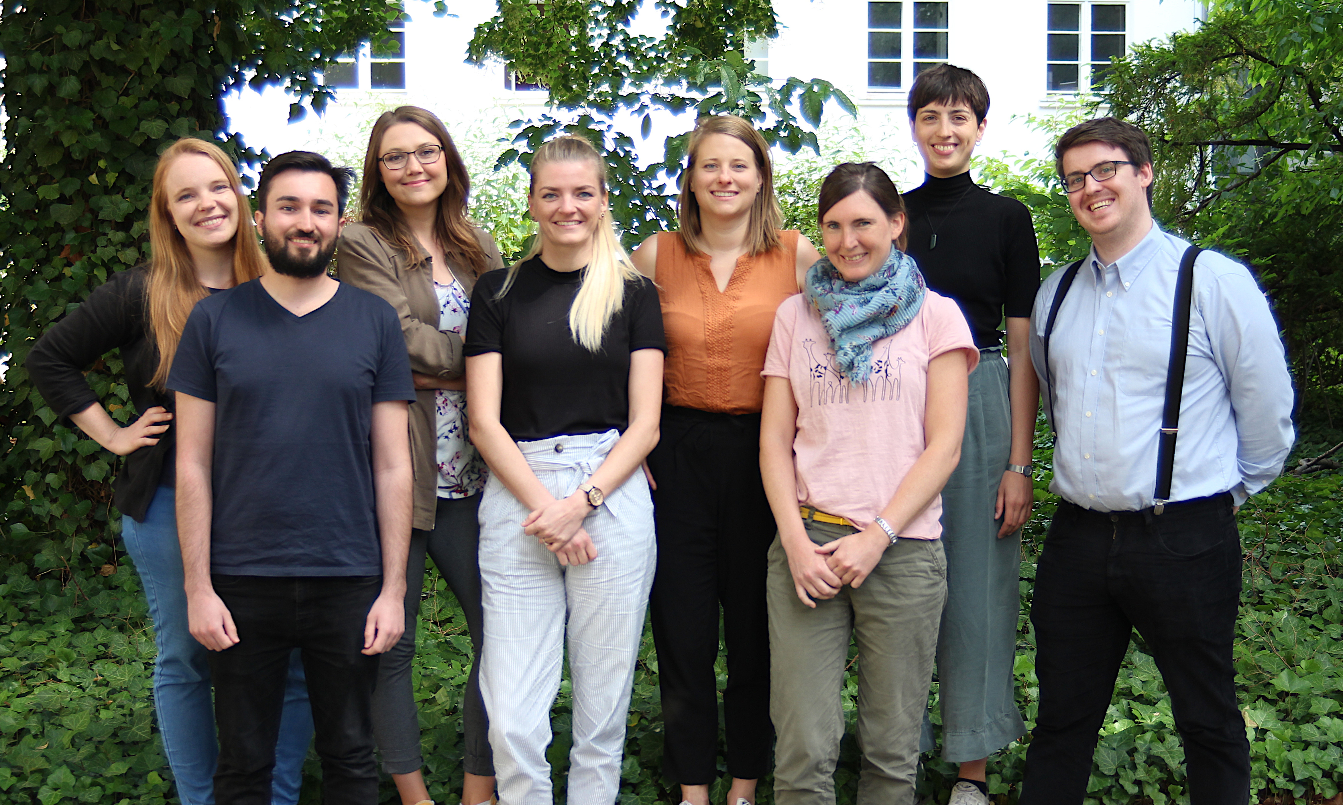 Teamfoto der Kompetenzzentren. Das Team steht vor grüner Natur im Freien