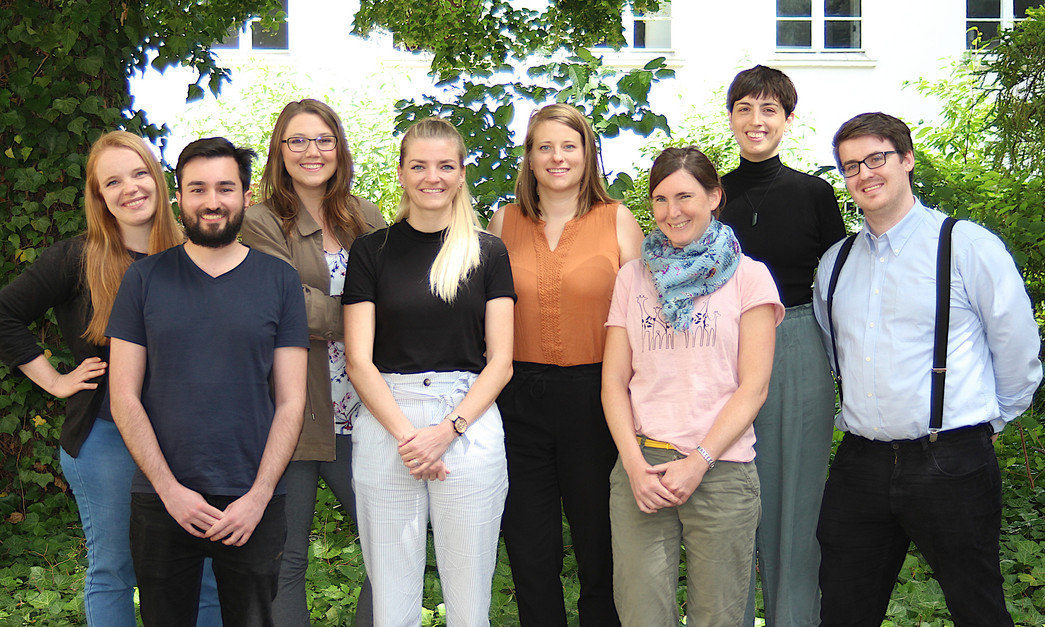 Das Team der Kompetenzzentren Digitalisierung Acht Menschen stehen auf einem Gruppenfoto und lächeln in die Kamera