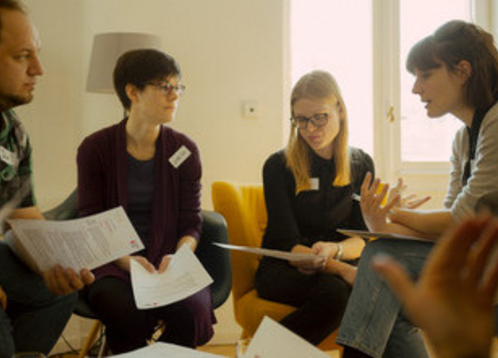 Vier Menschen sitzen in einer Gruppe zusammen und diskutieren.