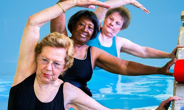 Drei Damen üben gerade Wassergymnastik 