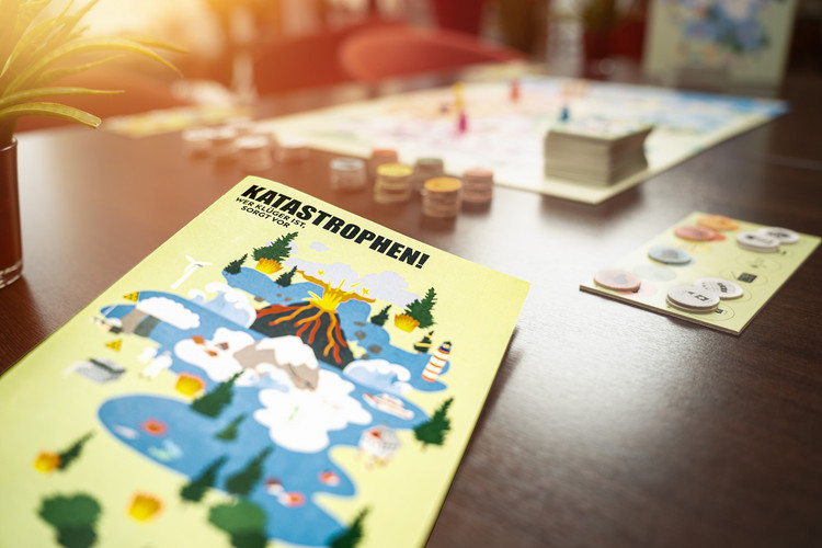 Brettspiel zum Thema Katastrophenschutz mit Spielanleitung, Spielbrett, Spielsteinen und Karten auf einem Tisch