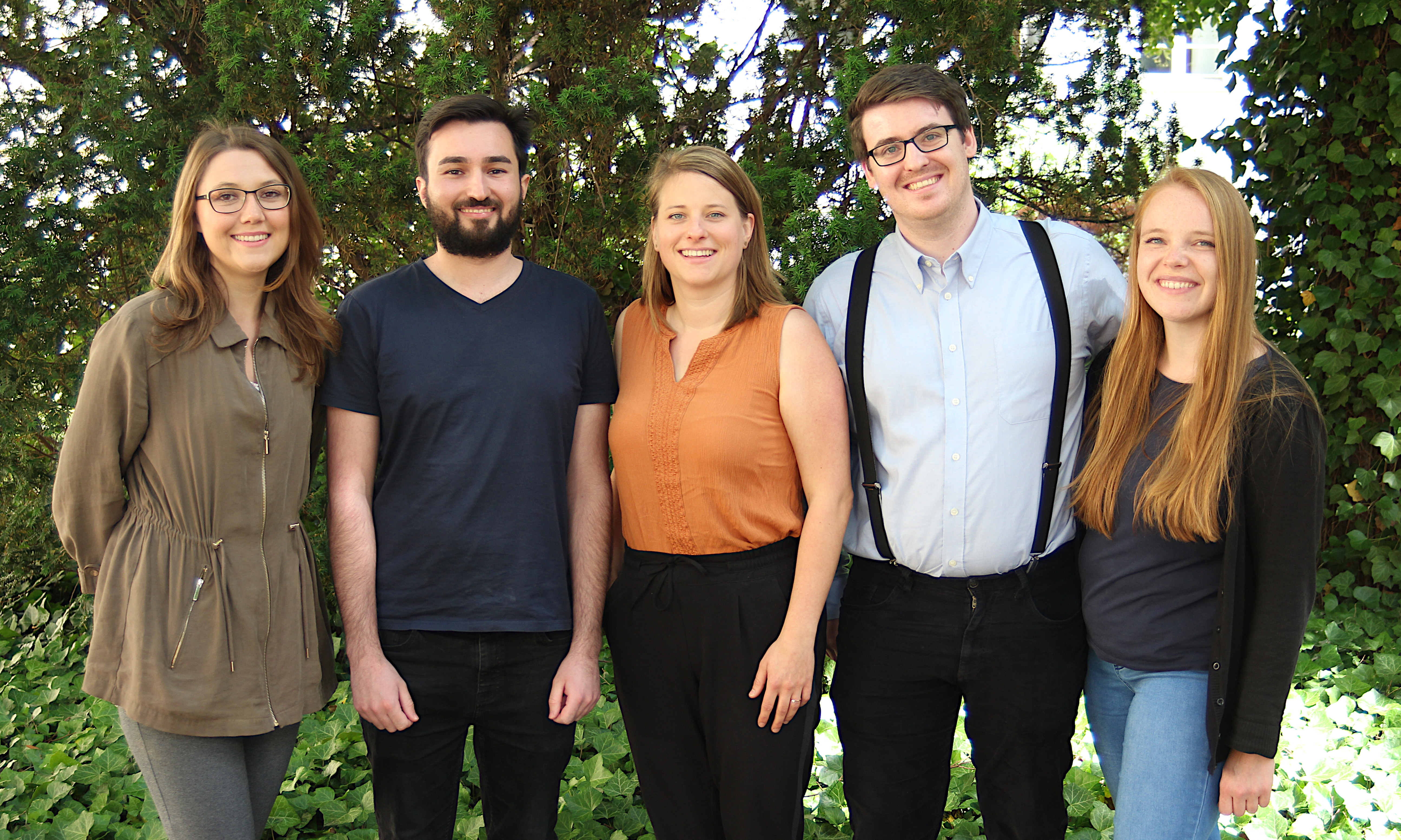 Gruppenfoto: Das Berliner Team vor einem Busch in Grün.