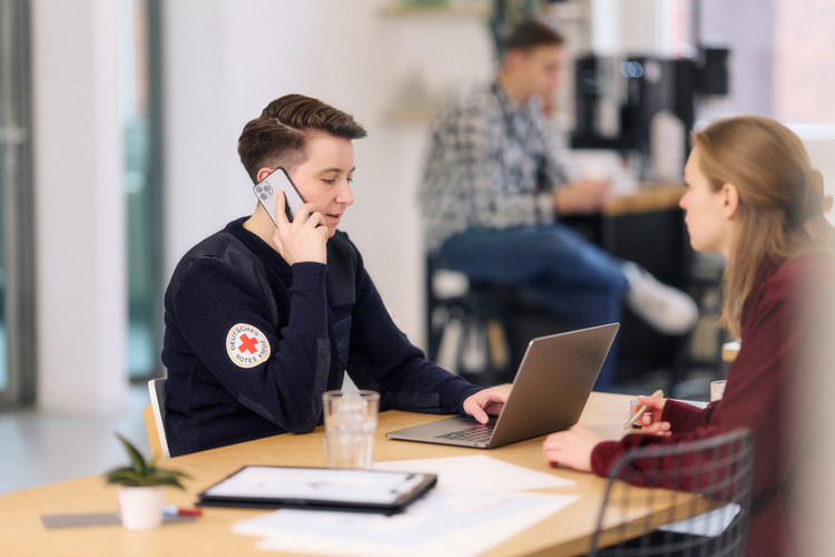Telefonierende Person am Schreibtisch mit Laptop