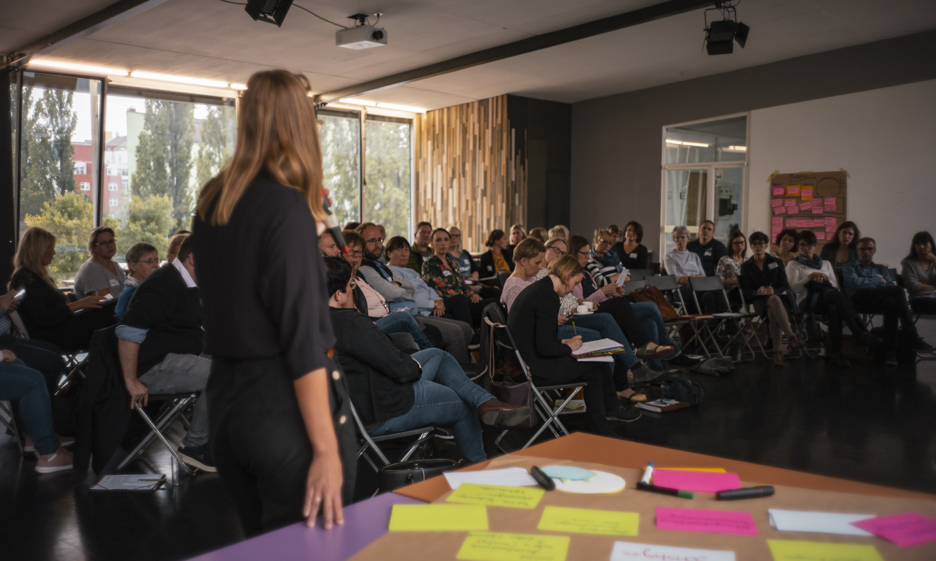 Kassandra steht vor den Teilnehmenden der Kita-Konferenz und moderiert.