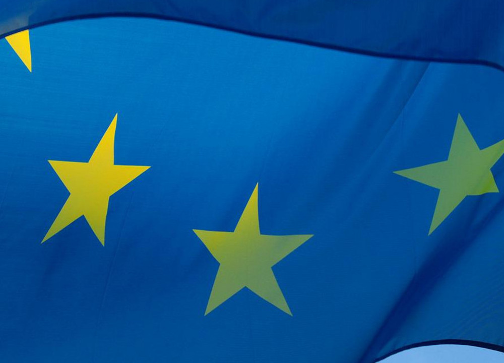 Wehende Europaflagge mit gelben Sternen auf blauem Grund vor klarem Himmel