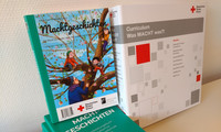 Mehrere Bücher mit dem Titel »Machtgeschichten« und ein Curriculum des Deutschen Roten Kreuzes liegen auf einem Tisch.