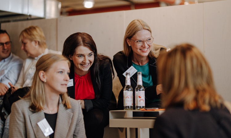 Auf dem Bild sieht man eine Gruppe Frauen, die zusammensitzen und sich unterhalten