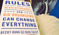 Buchcover mit dem Titel 'RULES FOR REVOLUTIONARIES. HOW BIG ORGANIZING CAN CHANGE EVERYTHING' von Becky Bond und Zack Exley in blauer und oranger Schrift.