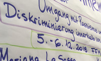 Handbeschriebene Flipchart mit Text zu einem Workshop über Rassismus und Diskriminierung, darunter Namen und Organisationen.
