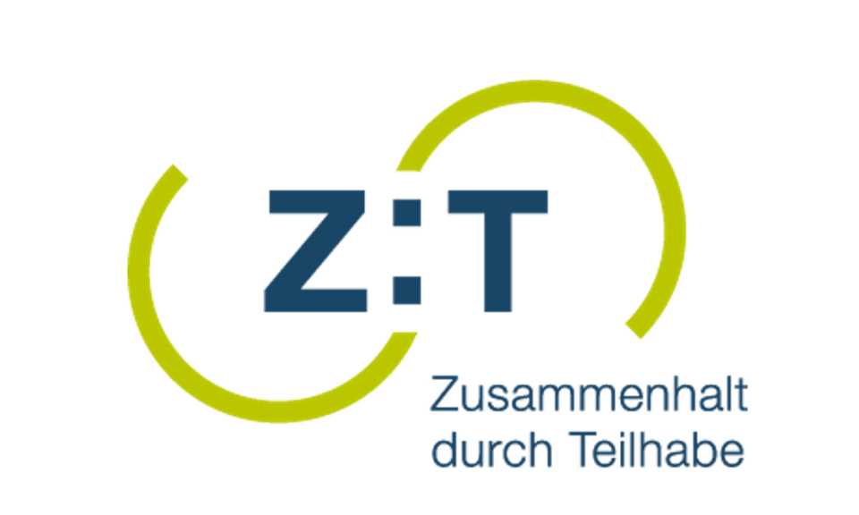In der Mitte steht "Z:T" beide Buchstaben sind von einem grünen Halbkreis umschlungen. Rechts unten steht Zusammenhalt durch Teilhabe.