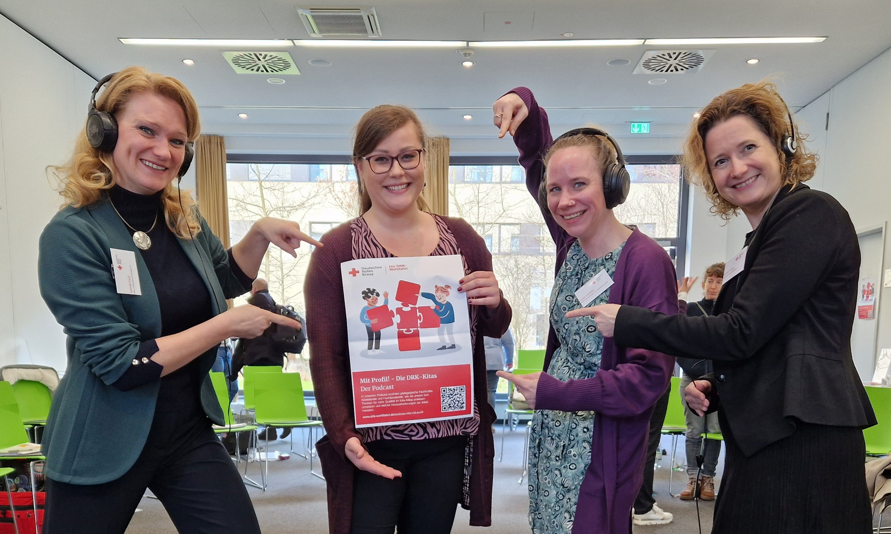 vier Frauen zeigen auf ein Plakat