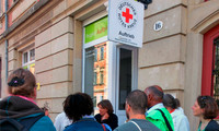 Menschen stehen vor einem Gebäude mit einem Schild des Deutschen Roten Kreuzes und der Aufschrift "Auftrieb".