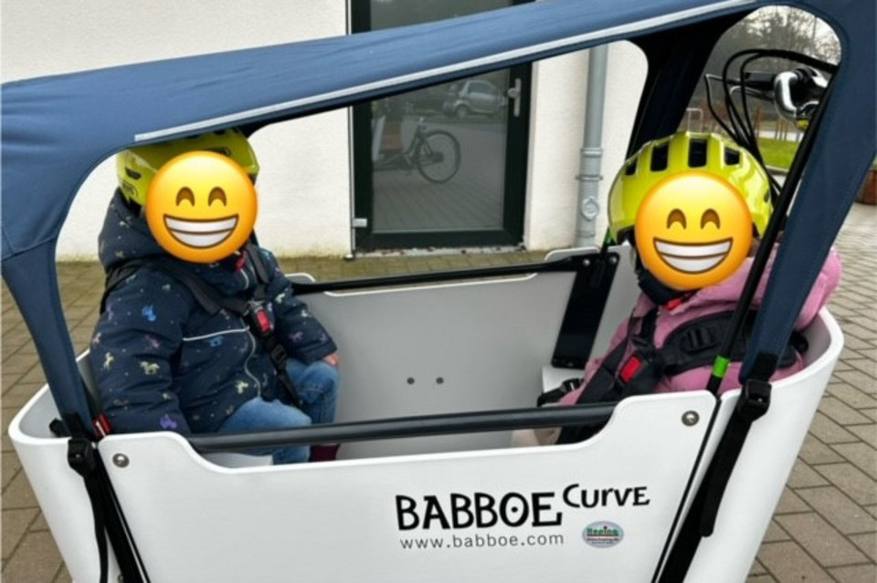 Zwei Kinder sitzen in einem Lastenrad