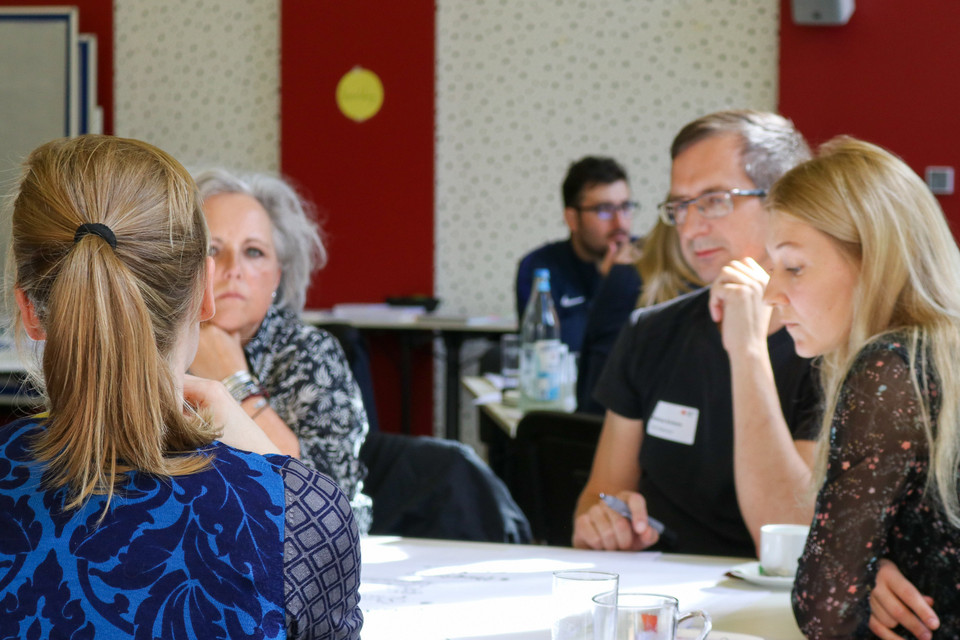 Teilnehmende eines Fachtages zum Thema Partizipation von Geflüchteten diskutieren am Tisch