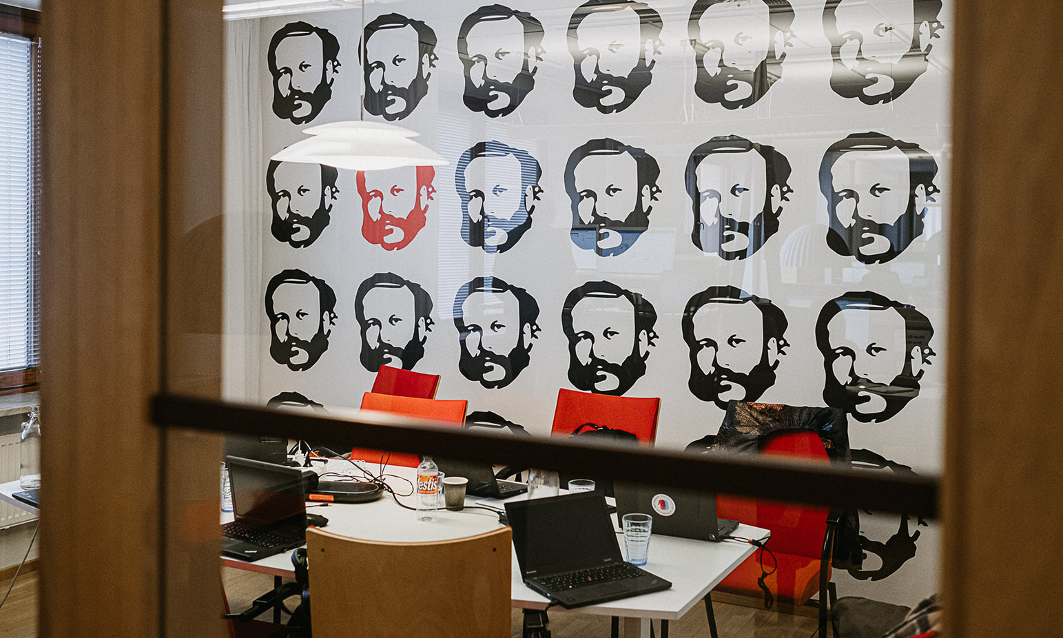 Digitalisierung im DRK mit Henry Dunant Auf dem Foto ist ein Ruam mit mehreren Laptops zu sehen, dahinter eine Fotowand mit der Siluette vom Kopf von Henry Dunant.