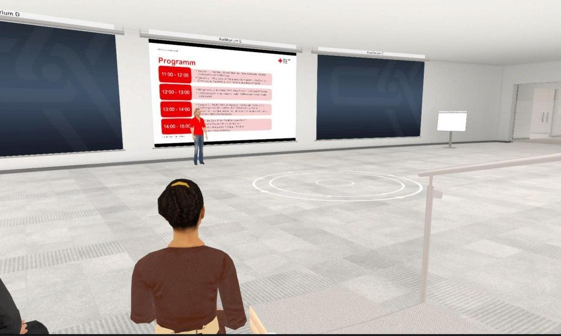 Im virtuellen Raum stellt ein Avatar die Agenda der Konferenz vor. Das Tagesprogramm ist abgebildet. 