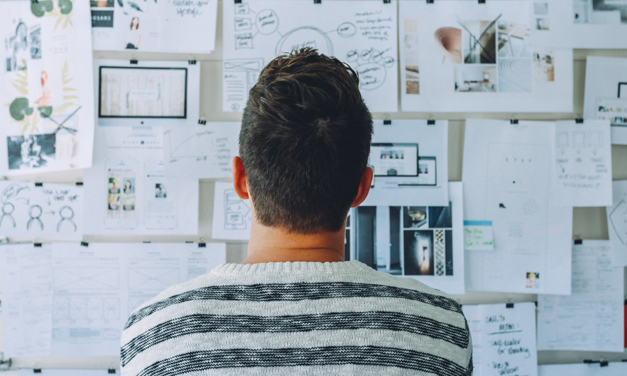 »Öffentliches Gestalten« – innovatives Arbeiten in der Verwaltung Person betrachtet Zettel auf Pinnwand.