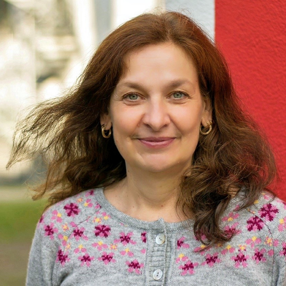 Frau lächelt in die Kamera mit Bäumen im Hintergrund