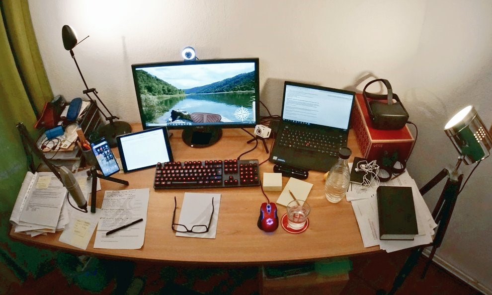 Ein Büroschreibtisch voller Büromaterialien, Unterlagen, einem Laptop und einem Monitor