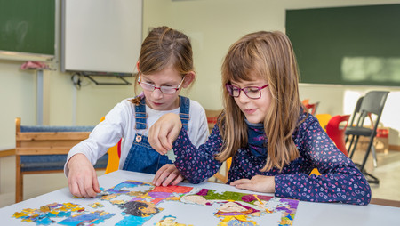 Schulkind und Klassenkameradin in der Schule beim Puzzlen