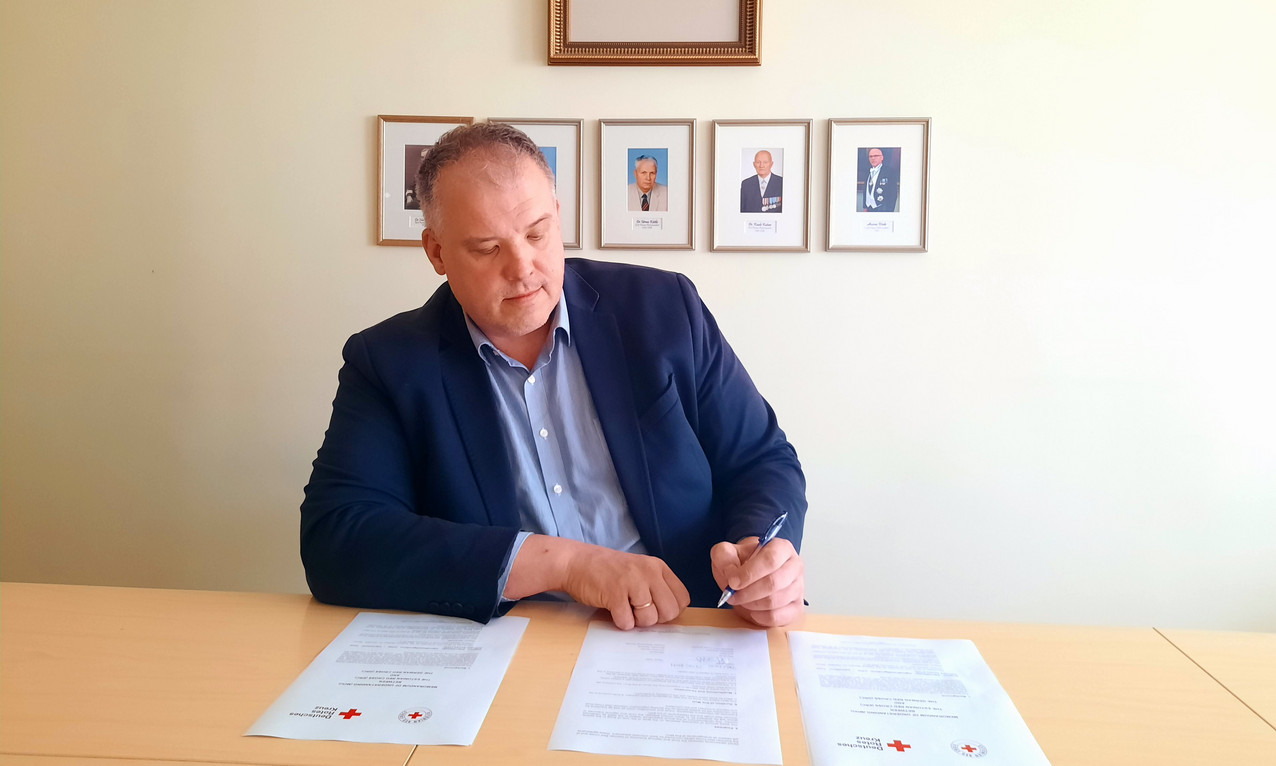 EstRK-Generalsekretär Perv sitzt am Schreibtisch und unterzeichnet das MoU. 
