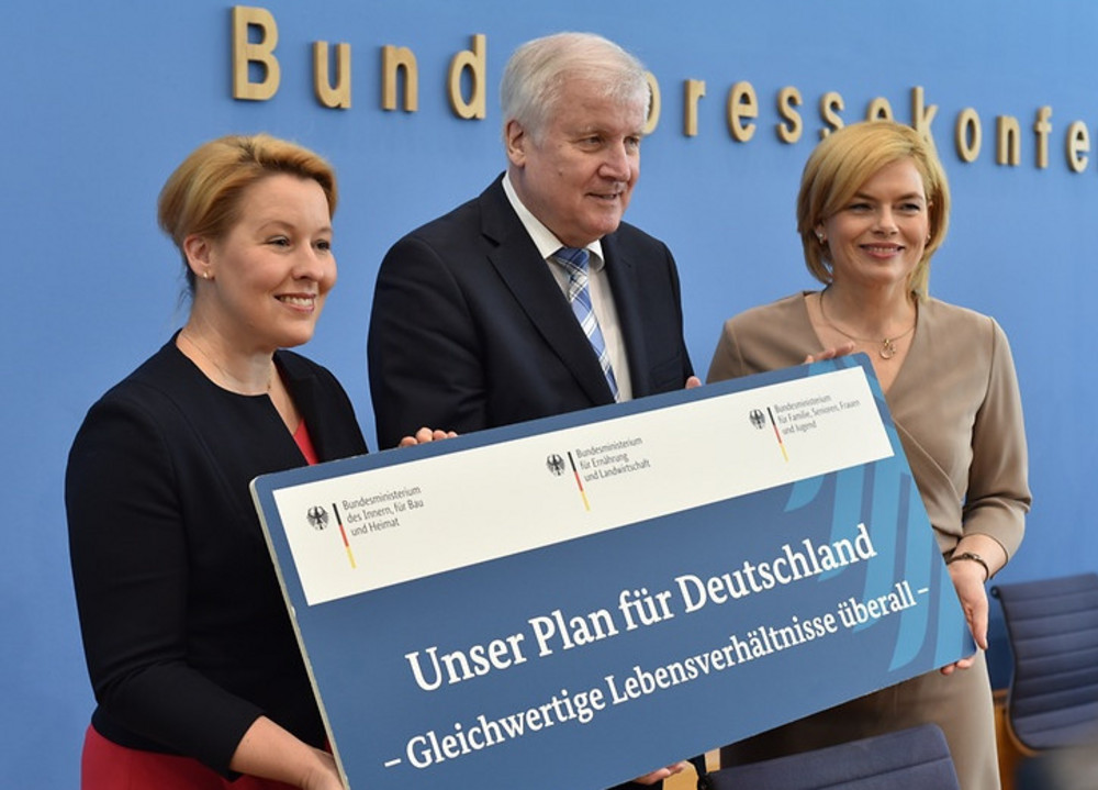 Franziska Giffey, Julia Klöckner und Horst Seehofer stehen vor einer Wand mit der Aufschrift 'Bundespressekonferenz' und halten ein Schild mit dem Text 'Unser Plan für Deutschland - Gleichwertige Lebensverhältnisse überall'