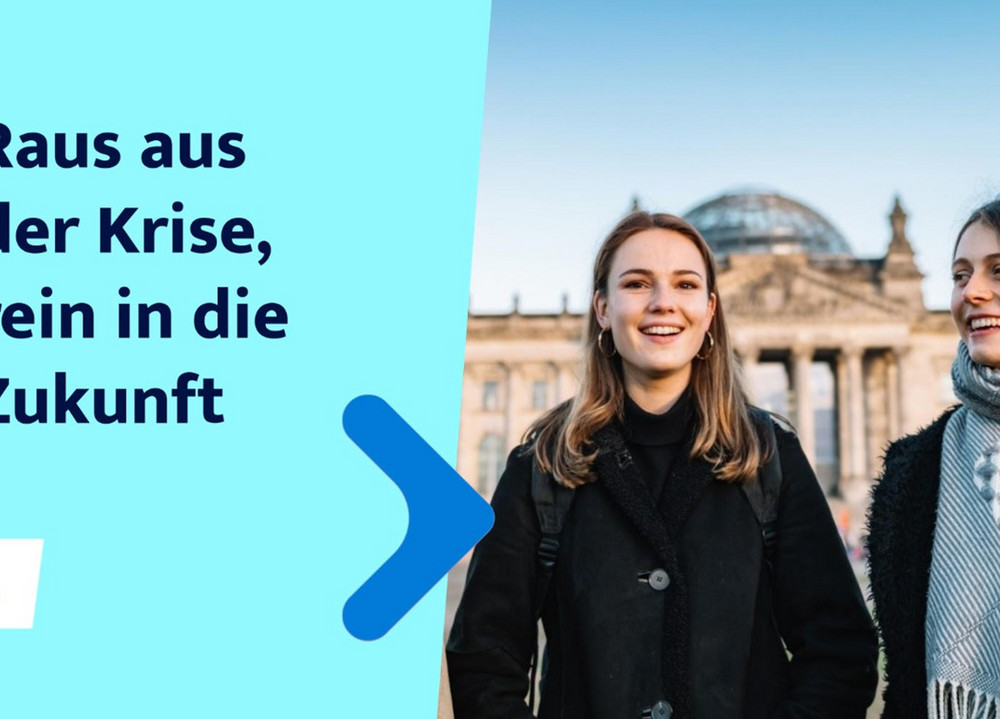 Links im Bild steht "Raus aus der Krise, rein in die Zukunft" - recht im Bild stehe zwei junge Frauen vor dem Reichstagsgebäude in Berlin.