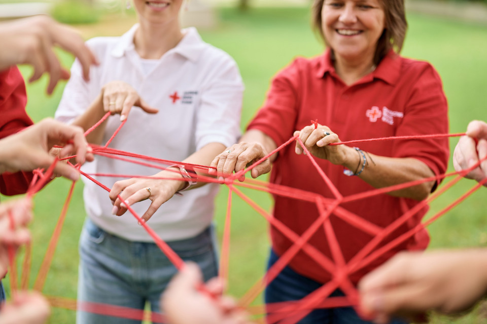 Menschen stehen zusammen und halten rote Schnüre in den Händen