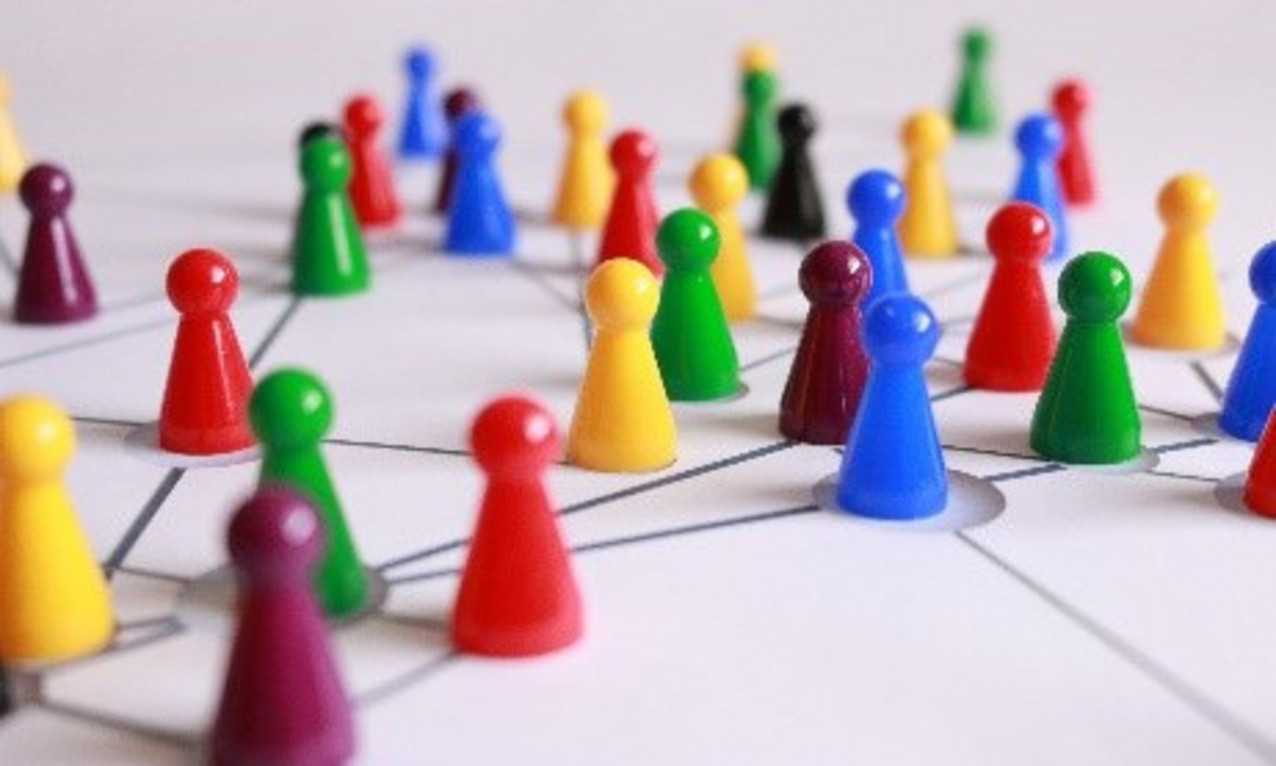 Viele Mensch-Ärger-Dich-Nicht-Spielfiguren in rot, blau, gelb und grün. Sie sind durch Lininen miteinander verbunden.