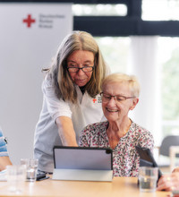 Senioren und Mitarbeitende des DRK vor einem Tablet