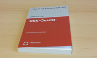Buch mit rot-weißem Umschlag mit dem Titel 'DRK-Gesetz' liegt auf hellem Holztisch.