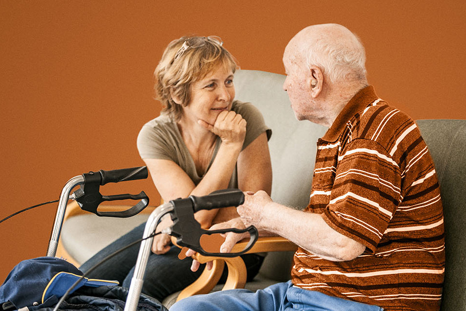 Aktivierungscoach und Mann im Rollator unterhalten sich 