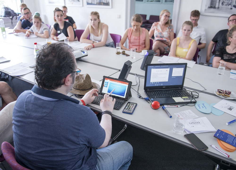 Eine Gruppe sitzt in einem Konferenzraum um einen Tisch.