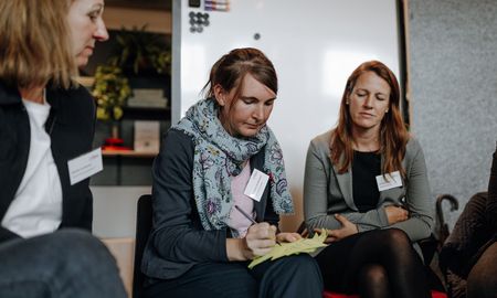 Auf dem Bild sieht man Beate Rottkemper, die mittig zwischen zwei Frauen sitzt und Notizen macht.