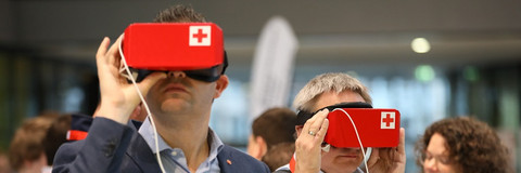 Zwei Männer halten VR-Brillen im DRK-Design.