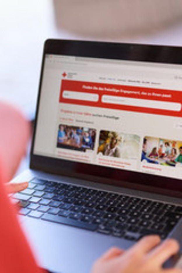 Person mit Laptop auf dem Schoss der eine offene DRK-Seite zeigt