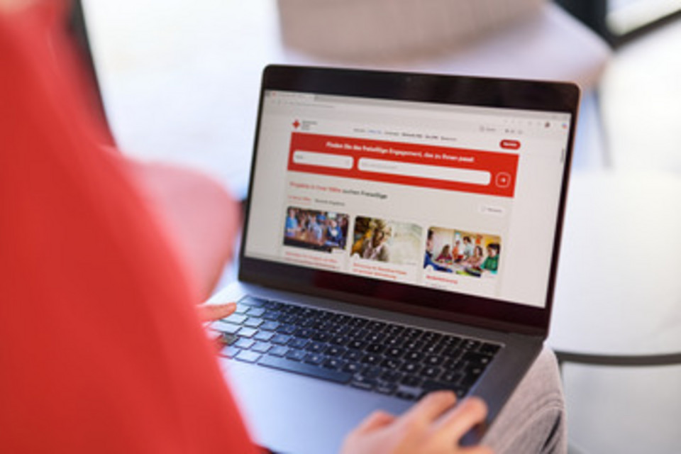 Person mit Laptop auf dem Schoss der eine offene DRK-Seite zeigt