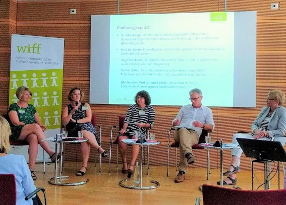 Menschen sitzen auf einem Podium und diskutieren