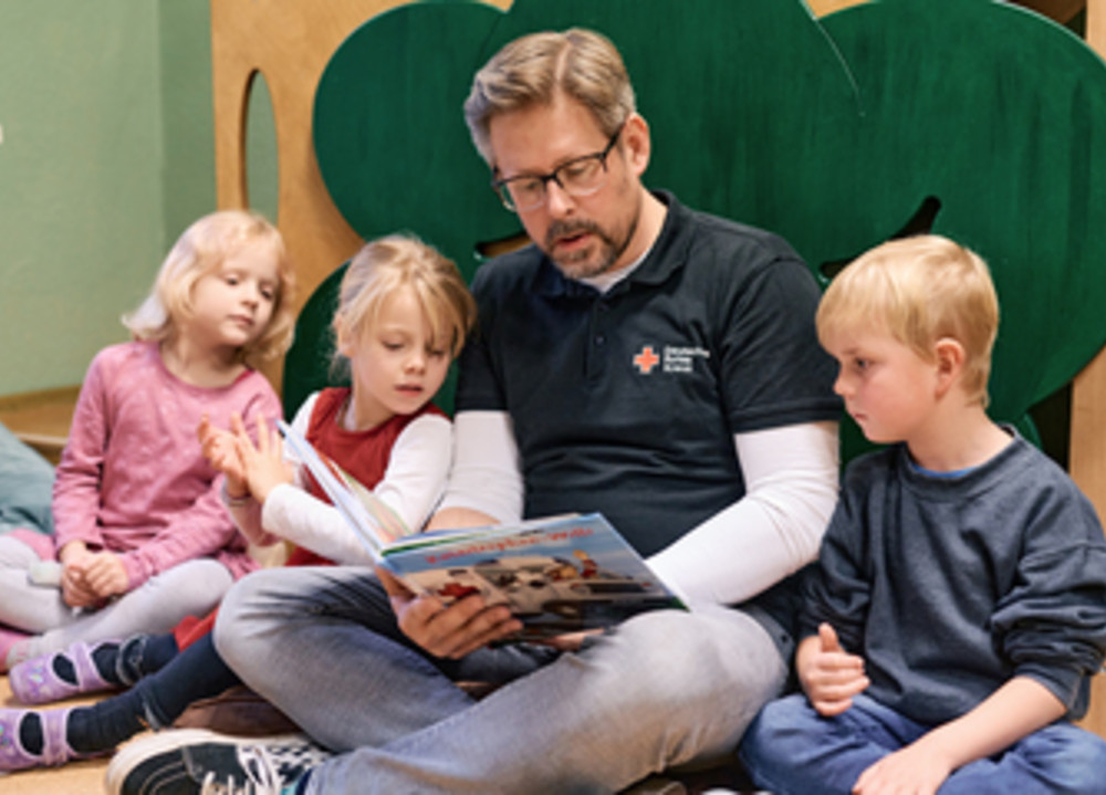 Erzieher liest Kindern vor