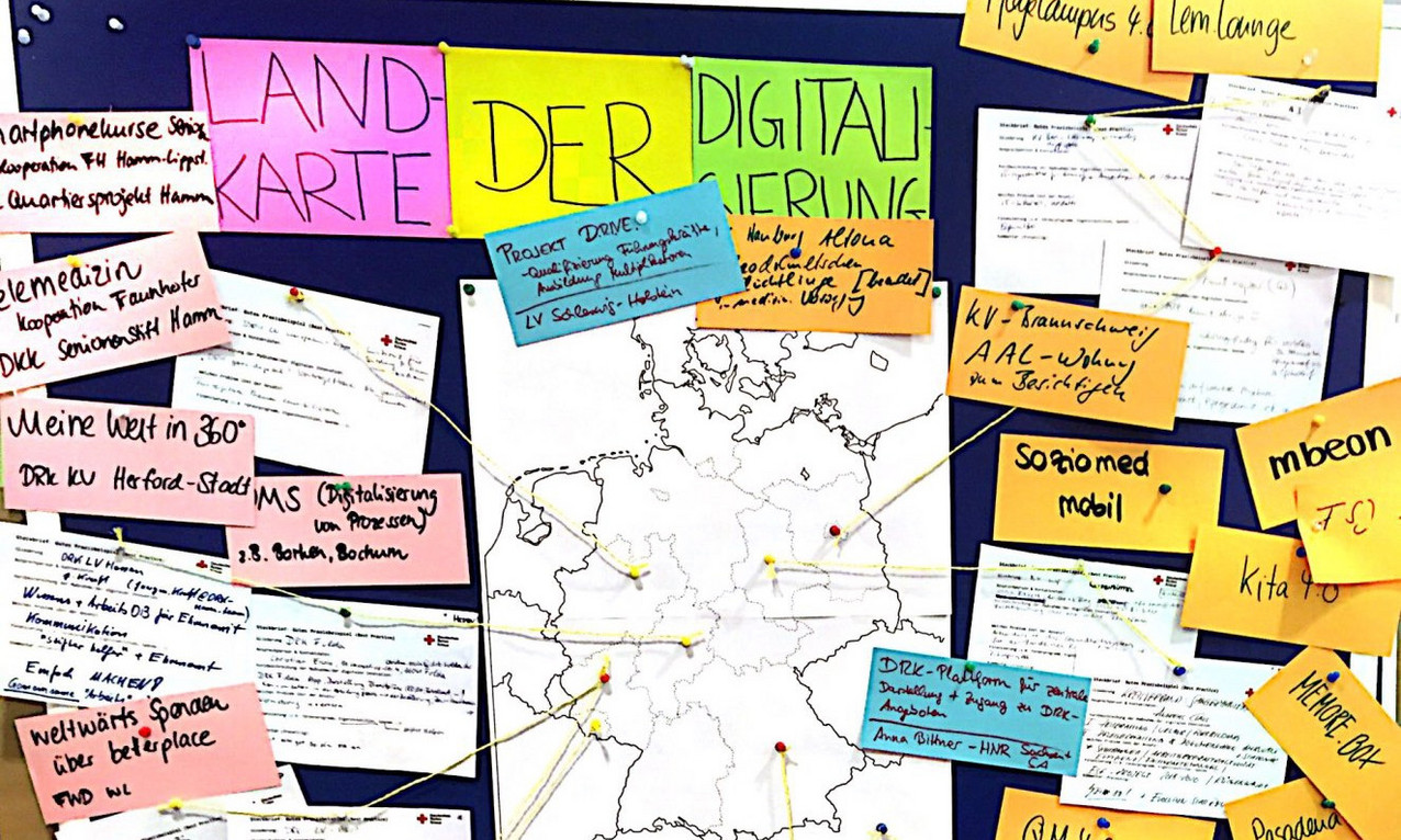 Eine Wand voller Post-Its, in der Mitte hängt eine Deutschlandkarte mit Linien und über ihr steht "Landkarte der Digitalisierung".