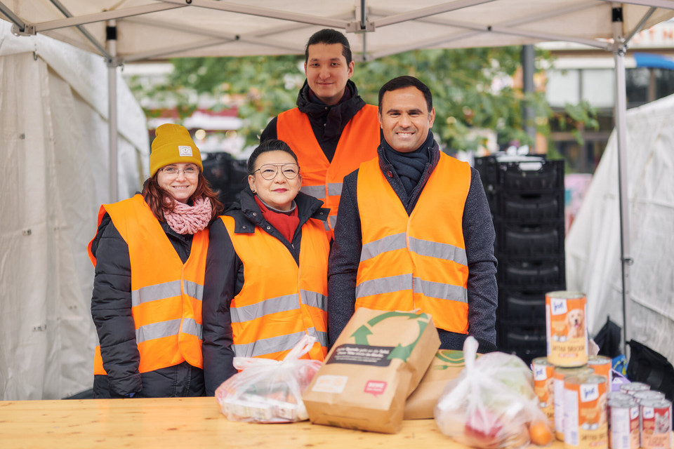 Vier Personen stehen vor einem Tisch mit Lebensmitteln