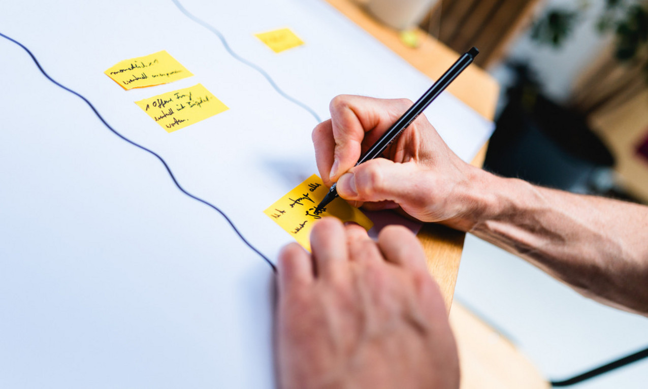 Hand schreibt auf Post It