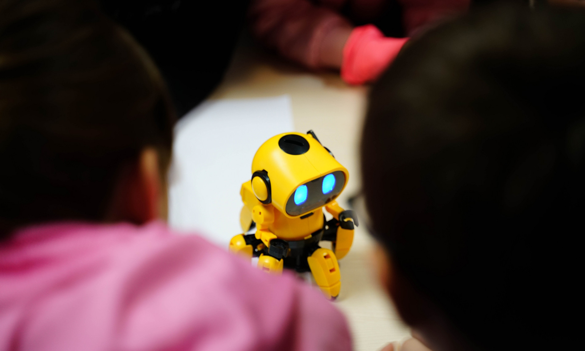 Kleiner gelber Roboter umringt von einer Kindergruppe