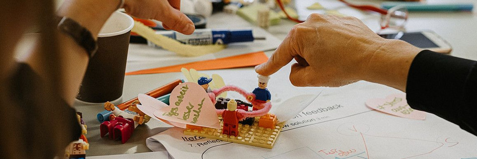 Prototyping mit Lego. Ein Finder wird auf eine Lego-Figur gedrückt.