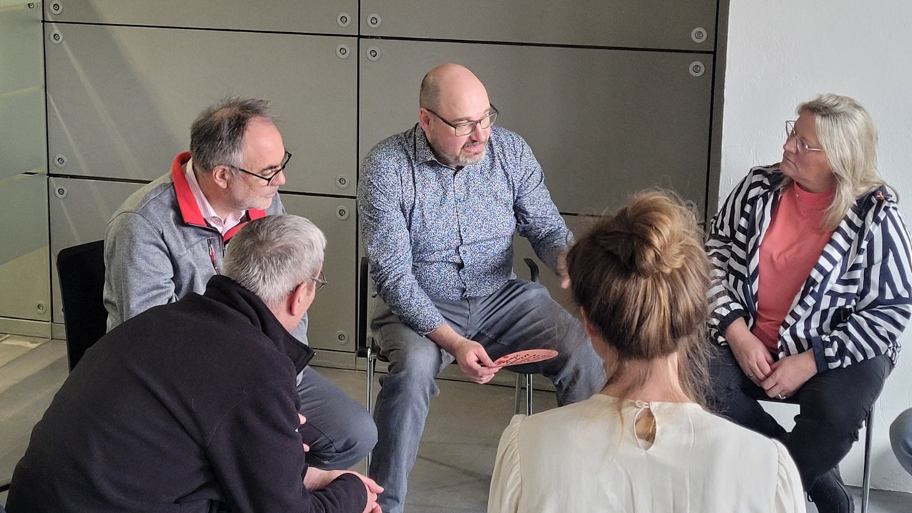 Alexander Voigt im Stuhlkreis, sprechend mit anderen Personen 