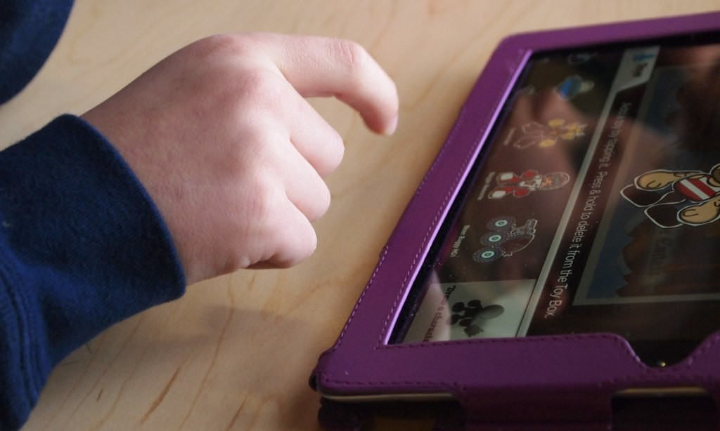 Eine Kinderhand tippt auf einem Computer-Tablet.