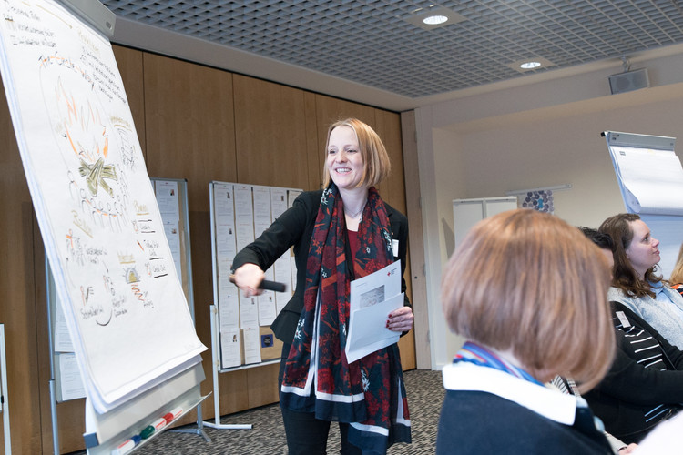 Frau erklärt etwas am FLipchart