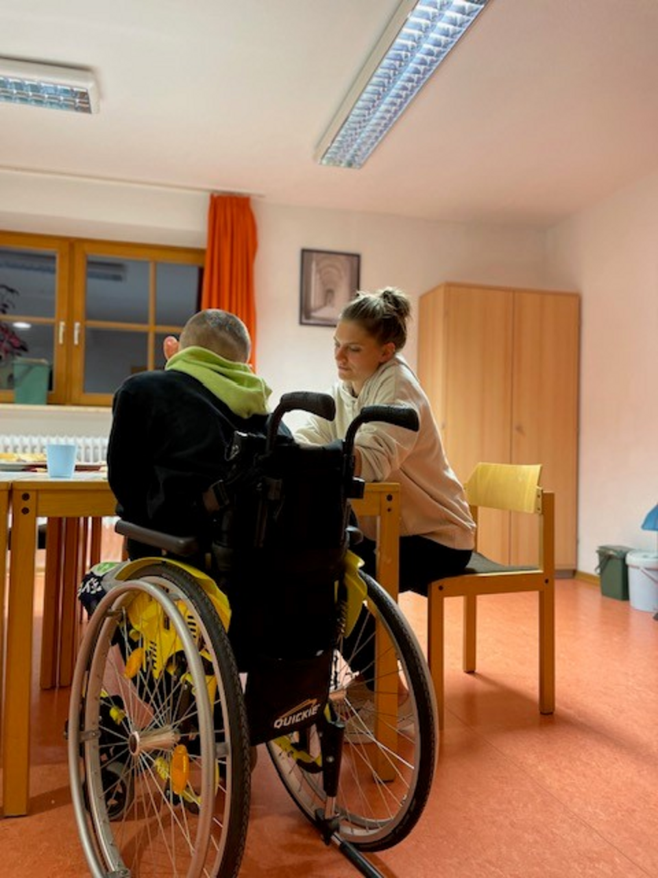 CJD Berchtesgaden im Rahmen der Unterbringung von vulnerablen minderjährigen Geflüchteten Kind mit Rollstuhl am Tisch mit Frau